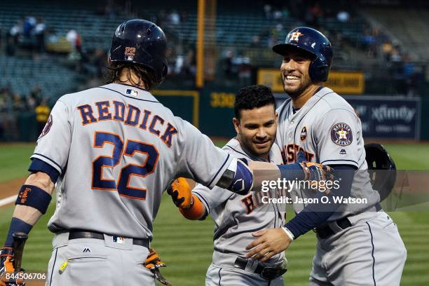 Jose Altuve of the Houston Astros is congratulated by George Springer and Josh Reddick after hitting a two-run home run against the Oakland Athletics...