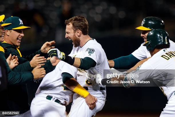 Jed Lowrie of the Oakland Athletics is congratulated by teammates after hitting a walk off single during the ninth inning against the Houston Astros...