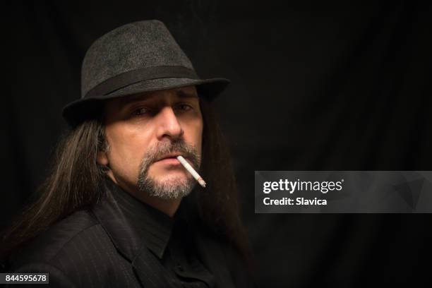 porträt von einem mittleren alter mann mit bart, schnurrbart und hut - zigarettenpause stock-fotos und bilder