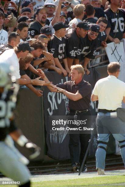 Jon Gruden head coach of the Oakland Raiders greets the fans in a game against the Denver Broncos at Oakland Coliseum circa 1999 in Oakland...