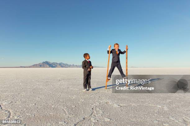 young businessman walking on stilts - stilt stock pictures, royalty-free photos & images