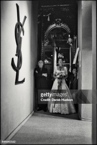 French fashion patron Pierre Berge and model & actress Laetitia Casta, in a wedding dress, stand in the wings during a Yves Saint Laurent haute...