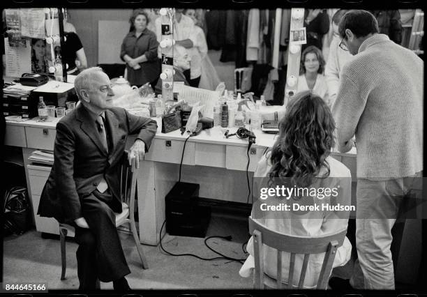 French fashion patron Pierre Berge sits backstage at a make-up table with a model during preparations for an Yves Saint Laurent haute couture runway...