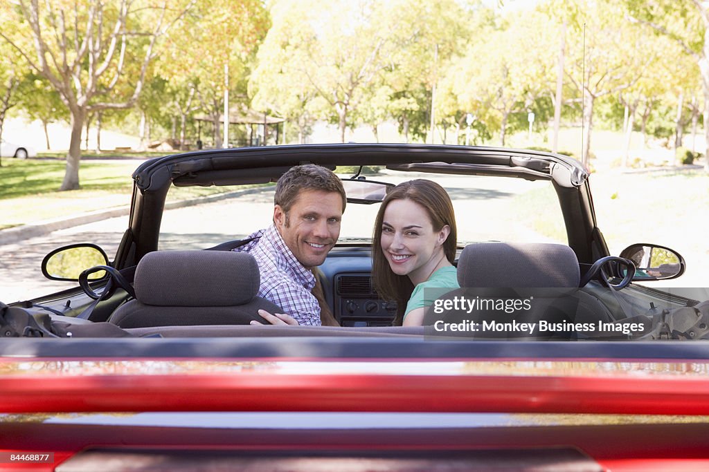 Couple in convertible car smiling