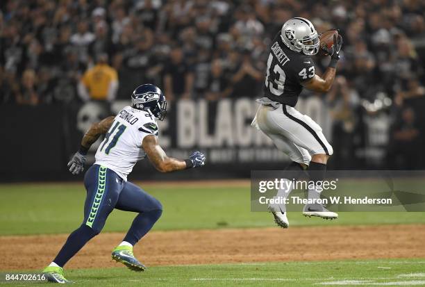 John Crockett of the Oakland Raiders catches a pass in front of Dewey McDonald of the Seattle Seahawks during the second quarter at Oakland-Alameda...