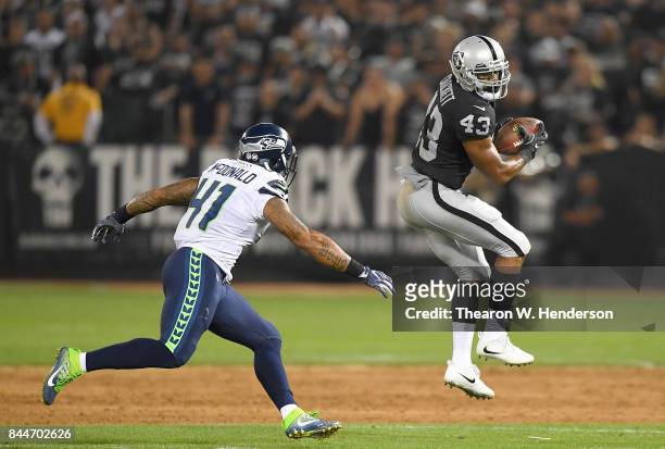 John Crockett of the Oakland Raiders catches a pass in front of Dewey McDonald of the Seattle Seahawks during the second quarter at Oakland-Alameda...