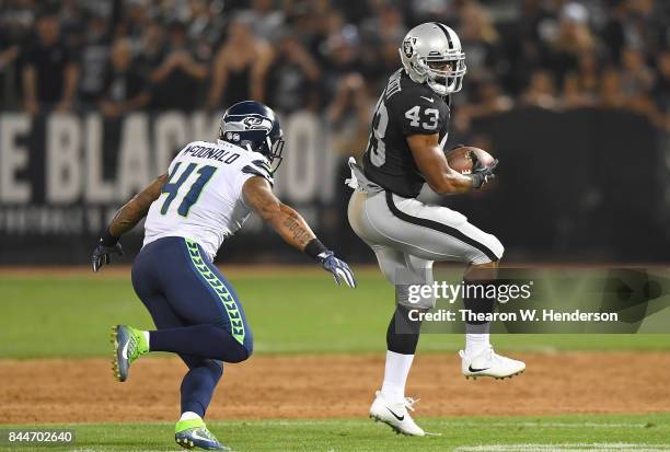 John Crockett of the Oakland Raiders catches a pass in front of Dewey McDonald of the Seattle Seahawks during the second quarter at Oakland-Alameda...