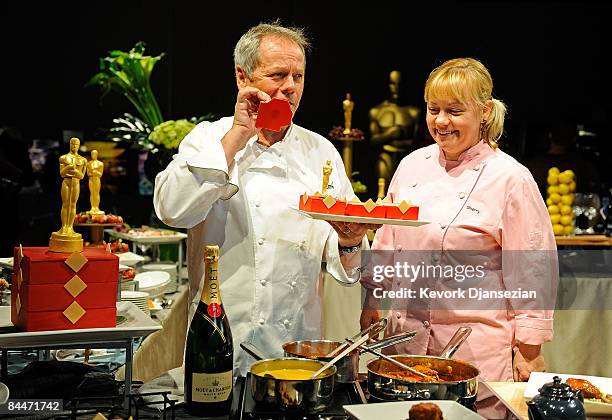 Master chef Wolfgang Puck takes bite of a golden choclate Oscar statue while holding a tray of choclate bento boxes as Sherry Yard, executive pastry...