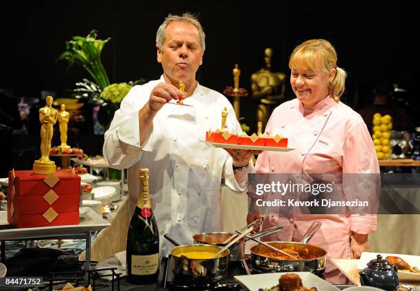 Master chef Wolfgang Puck takes bite of a golden choclate Oscar statue while holding a tray of choclate bento boxes as Sherry Yard, executive pastry...