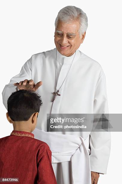 priest blessing a boy and smiling - senior pastor stockfoto's en -beelden