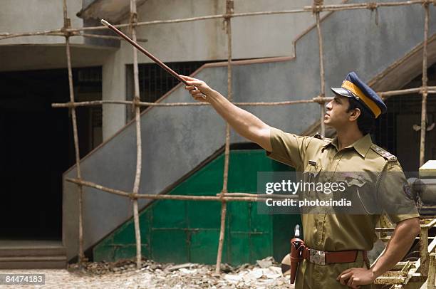 policeman pointing forward with a nightstick - truncheon stockfoto's en -beelden