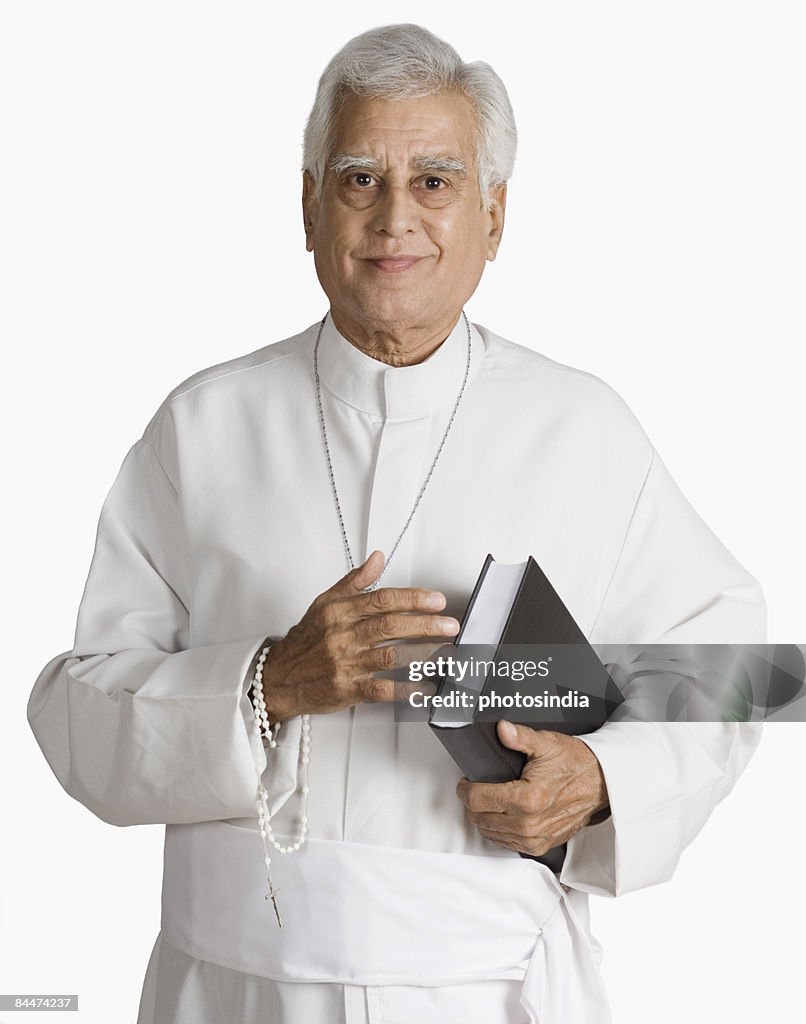 Portrait of a priest holding the Bible and smiling