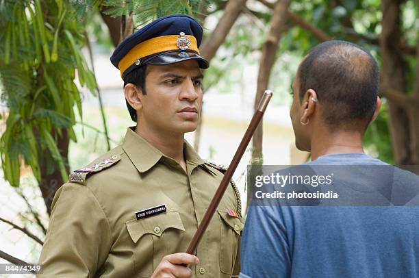 close-up of a policeman showing a nightstick to a young man - indian police officer image with uniform stock-fotos und bilder