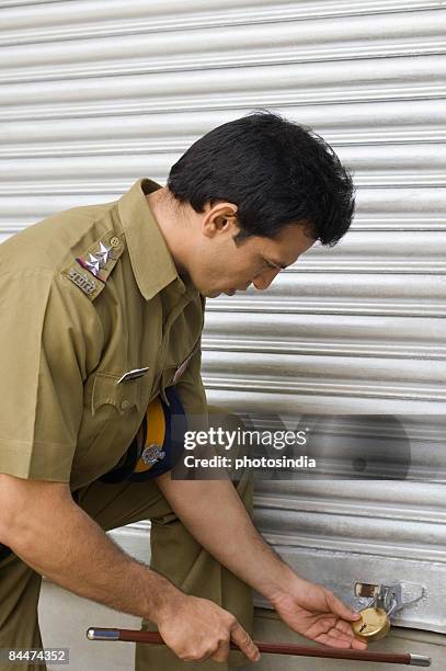 side profile of a policeman holding the padlock of a store - indian police officer image with uniform stockfoto's en -beelden