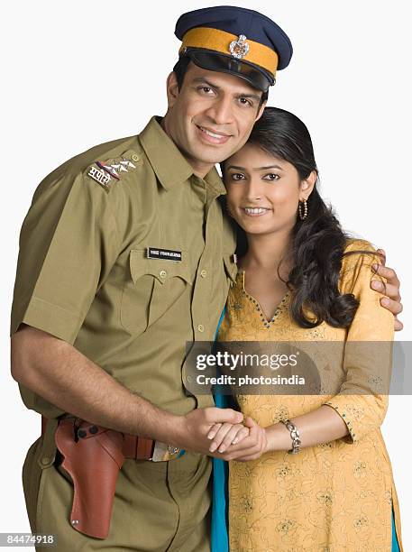 portrait of a police officer standing with his arm around his wife - indian police officer image with uniform stockfoto's en -beelden