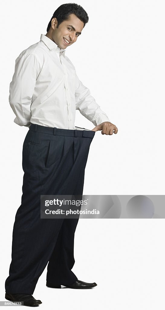 Portrait of a young man stretching his pant and smiling