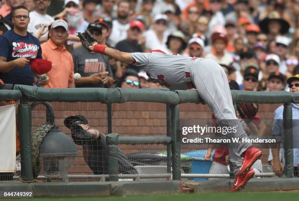 Alex Mejia of the St. Louis Cardinals goes over the rail after a foul ball off the bat of Joe Panik of the San Francisco Giants in the bottom of the...