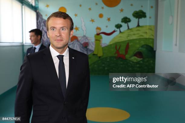 French President Emmanuel Macron stands in front of a mural with an image from "The Little Prince" as he arrives for a presentation of a 3D model of...