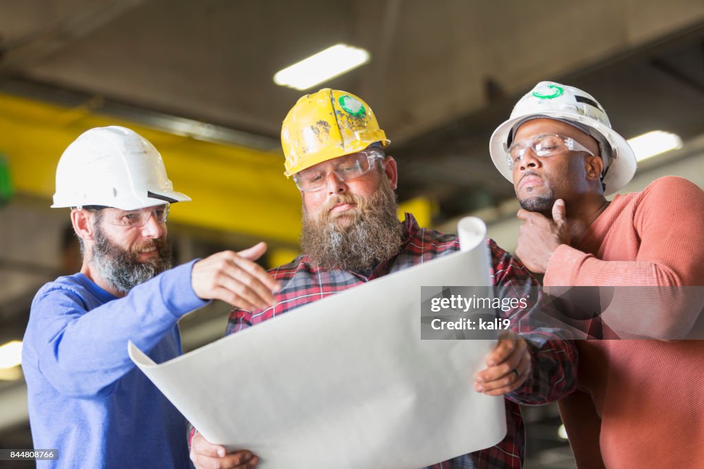 Multi-ethnic workers in hardhats examining plans