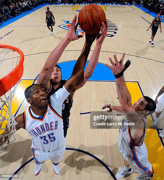 Josh Boone of the New Jersey Nets goes for a rebound against Kevin Durant and Nick Collison of the Oklahoma City Thunder at the Ford Center on...