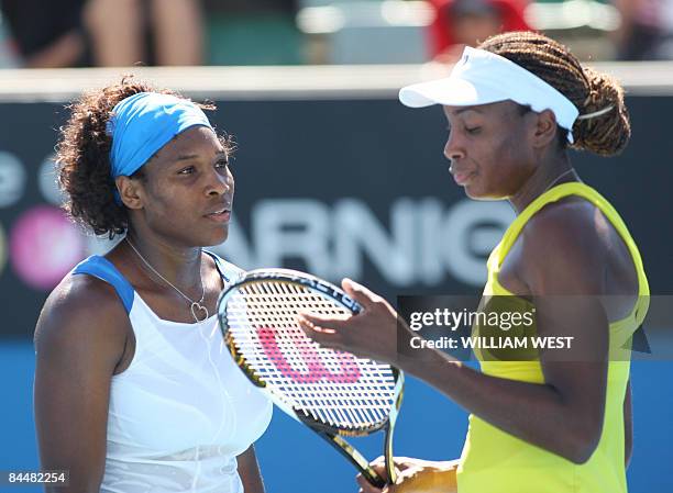 Venus and Serena Williams of the US discuss their game plan against Peng Shuai of China and partner Hsieh Su-Wei of Taiwan during their women's...