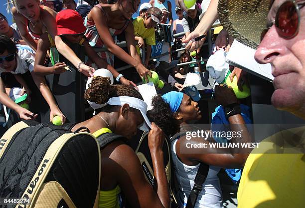 Venus and Serena Williams of the US sign autographs for spectators before their women's doubles match against Peng Shuai of China and Hsieh Su-Wei of...