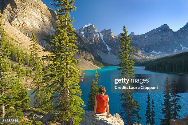 woman sitting on rock at lake moraine - moraine lake stock-fotos und bilder
