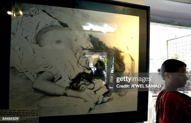 In this file photo taken on March 25, 2001 a Bangladeshi school student is reflected in glass covering a photograph of a Bangladeshi rape victim...