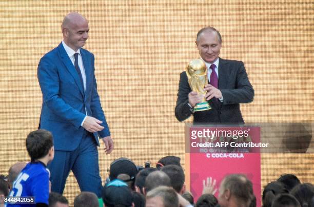 Russian President Vladimir Putin holds the FIFA World Cup Trophy flanked by FIFA President Gianni Infantino during the opening of the trophy tour...