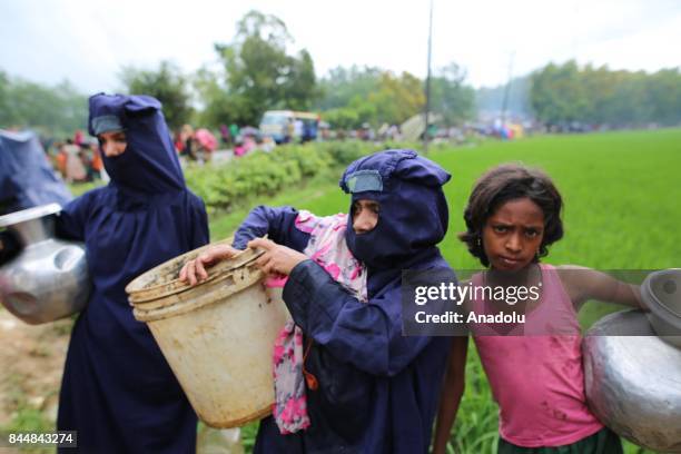 Rohingya Muslim women, fled from ongoing military operations in Myanmars Rakhine state, carry buckets at a makeshift refugee camp in Cox's Bazar,...