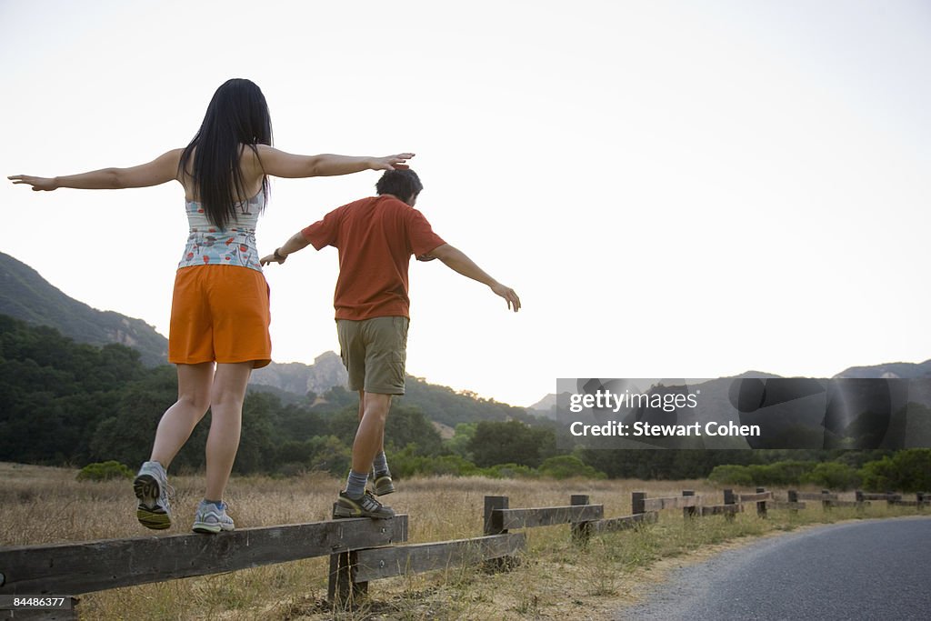Active couple balancing on low fence.
