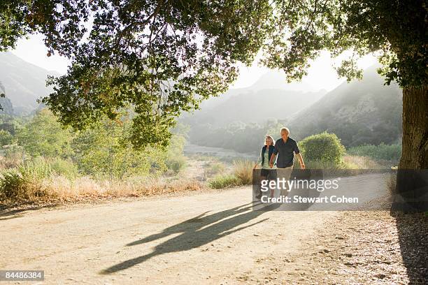 active mature couple walking down scenic road - daily life in southern california stockfoto's en -beelden