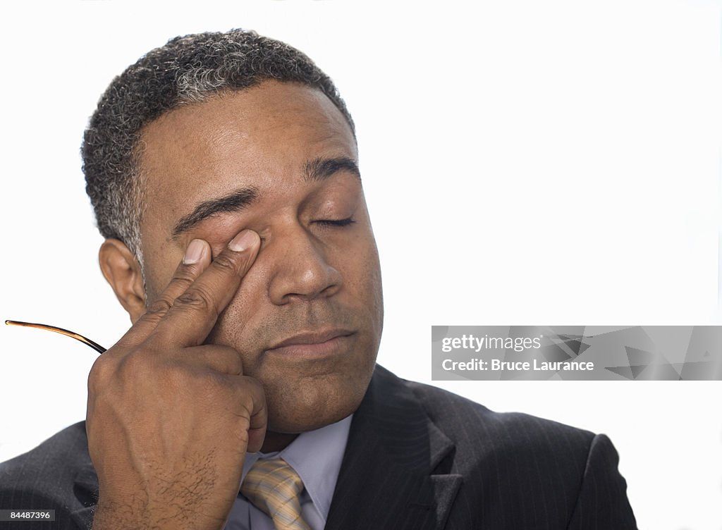 Businessman rubbing his eye