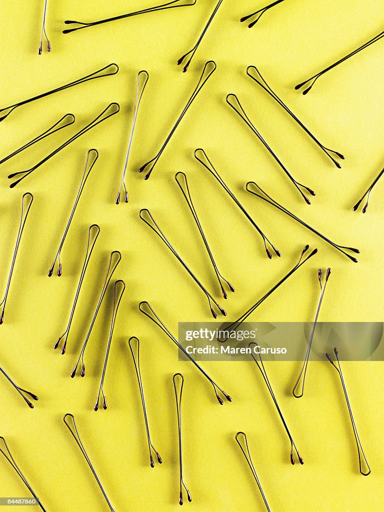 Bobby pins on a yellow surface.
