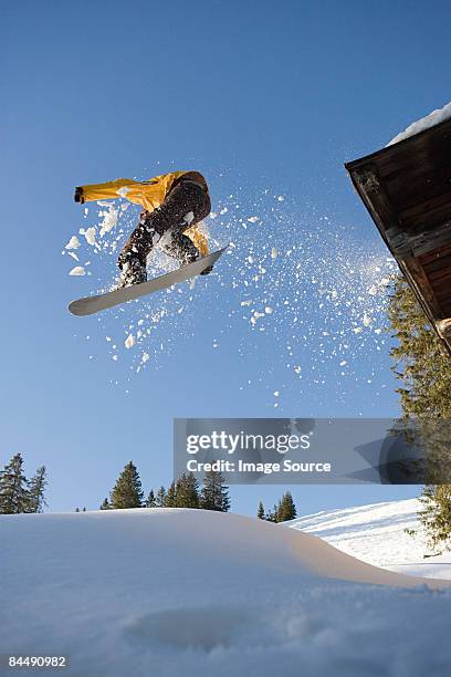 a snowboarder jumping off a cabin roof - snowboard jump bildbanksfoton och bilder