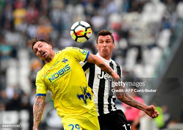 Juventus' Croatian forward Mario Mandzukic vies with Chievo's Italian defender Fabrizio Cacciatore during the Italian Serie A football match Juventus...