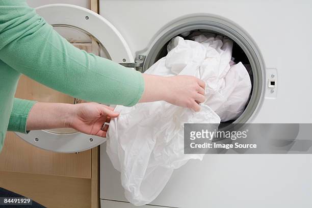 woman taking sheet from washing machine - bedding stock pictures, royalty-free photos & images
