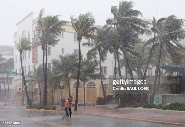 People walk down the street as winds and rain begin to hit as outer bands of Hurricane Irma arrive in Miami Beach, Florida, September 9, 2017. -...