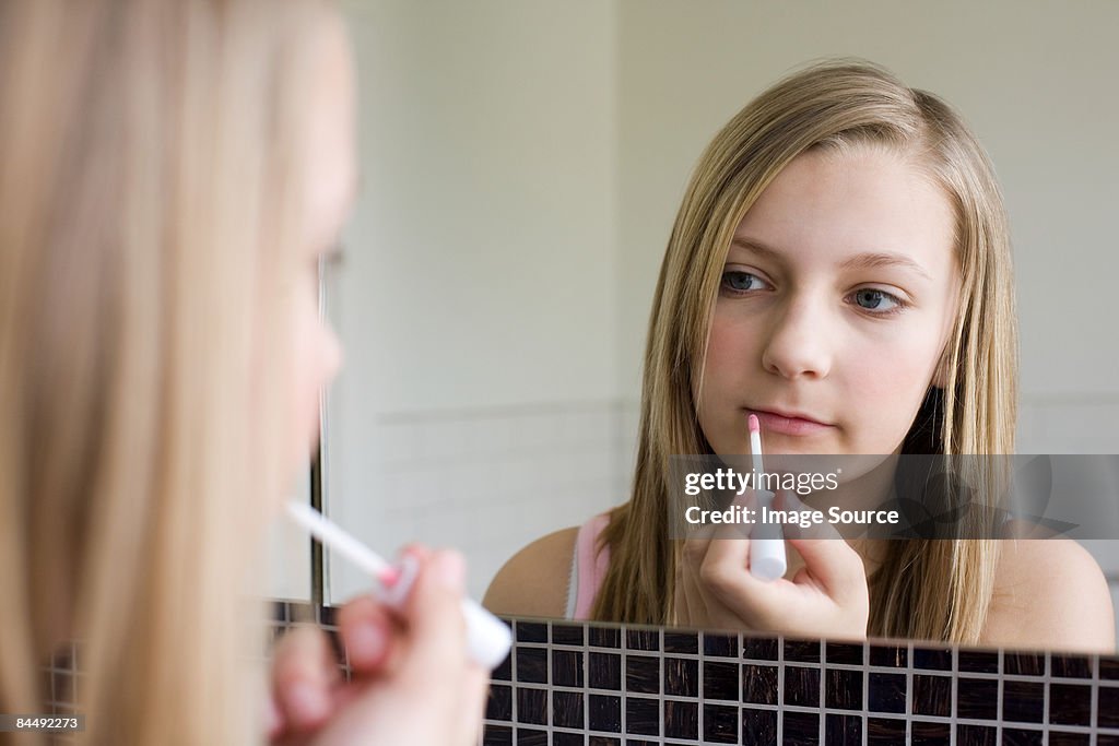 A teenage girl applying lipgloss