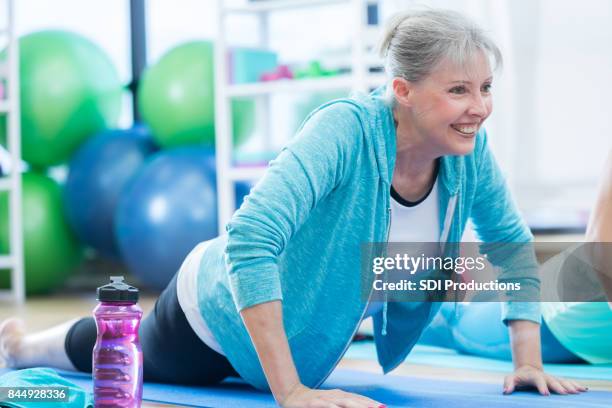 senior kvinna leenden under yogaställning på gym - floor gymnastics bildbanksfoton och bilder