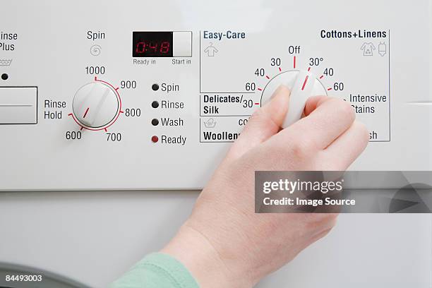 person turning dial on washing machine - hand wasser stockfoto's en -beelden