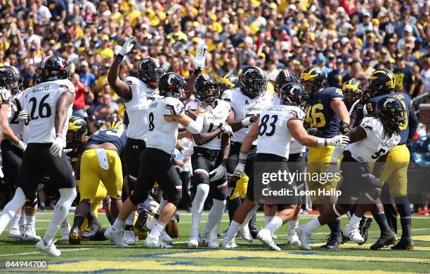 Mike Boone of the Cincinnati Bearcats scores on a one yard run and celebrates with his team during the first quarter of the game against the Michigan...