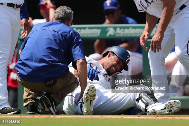 Carlos Gomez of the Texas Rangers winces in pain after rolling his ankle running to first base in the second inning of a game against the New York...