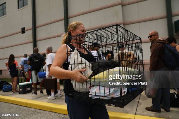 Woman carries her dog as people arrive at a shelter at Alico Arena where thousands of Floridians are hoping to ride out Hurricane Irma on September...