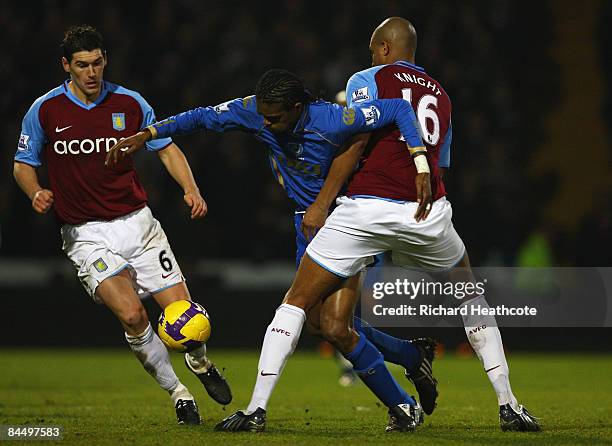 Kanu of Portsmouth is held up by Zat Knight and Gareth Barry of Aston Villa during the Barclays Premier League match between Portsmouth and Aston...
