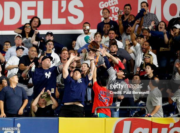 Fans try to catch a home run ball hit by Gary Sanchez of the New York Yankees in an MLB baseball game against the Boston Red Sox August 31, 2017 at...