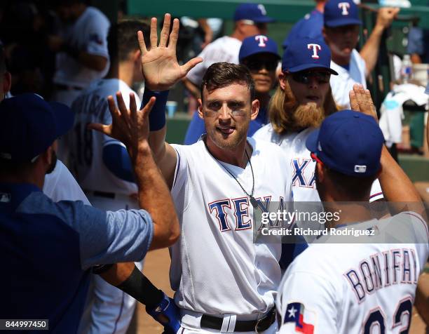 Will Middlebrooks of the Texas Rangers gets high fives in the dugout after scoring in the 5th inning against the New York Yankees at Globe Life Park...