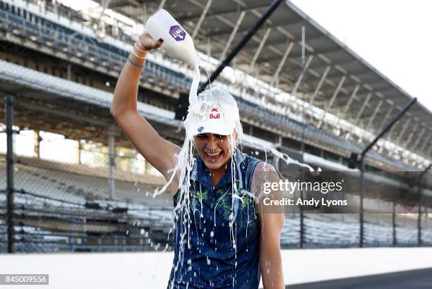 Lexi Thompson pours milk on her head while standing on the race track at the Indianapolis Motor Speedway after winning the Indy Women In Tech...