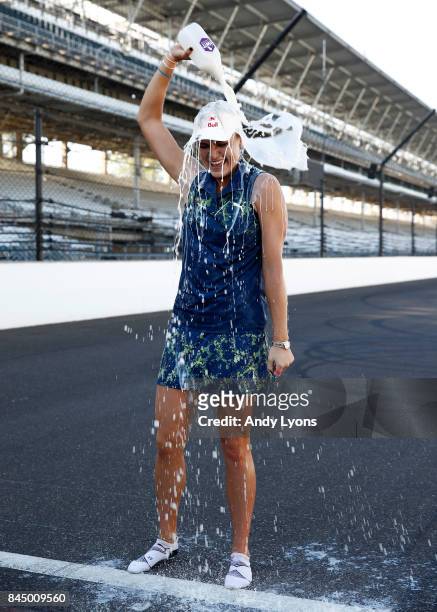 Lexi Thompson pours milk on her head while standing on the race track at the Indianapolis Motor Speedway after winning the Indy Women In Tech...