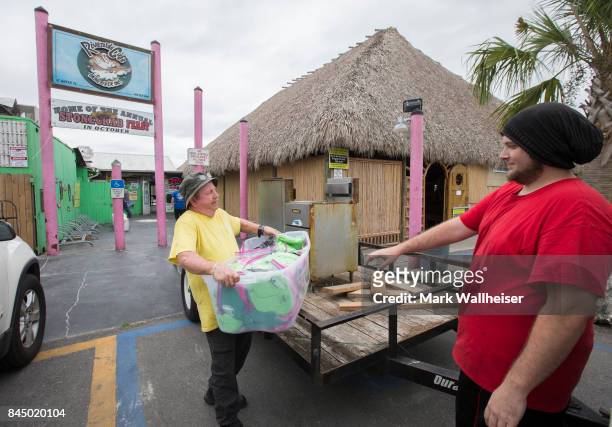 Stan West, left, owner of the Riverside Cafe hands off supplies to Tyler Lindsey as they evacuate the restaurant in preparation for Hurricane Irma...